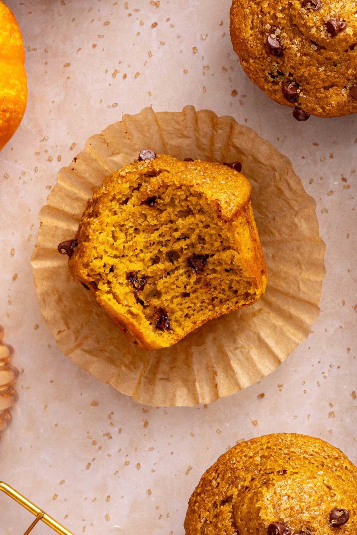 Pumpkin muffin on a muffin liner with a bite taken out.