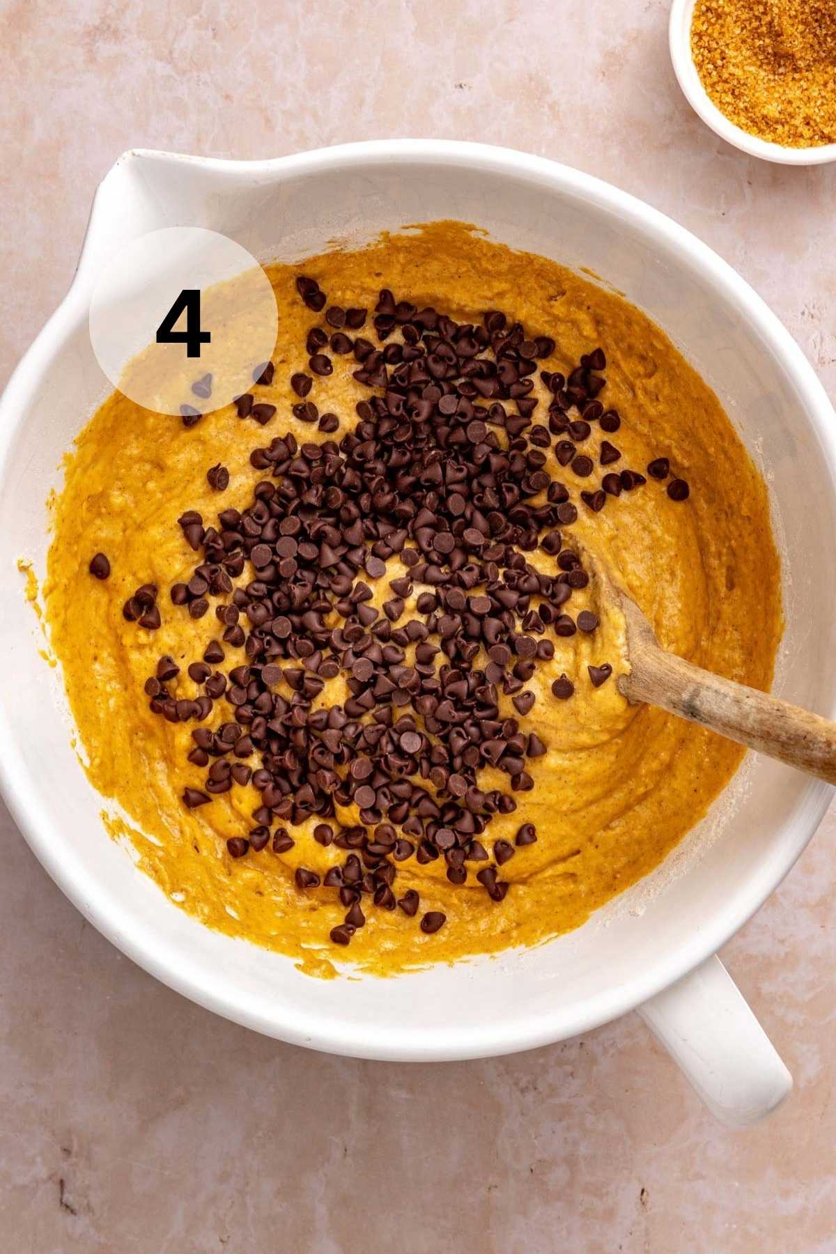 Stirring chocolate chips into pumpkin muffin batter.