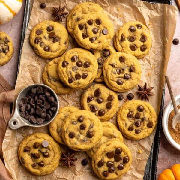 Chocolate chip pumpkin cookies on a cookie sheet lined with parchment paper.