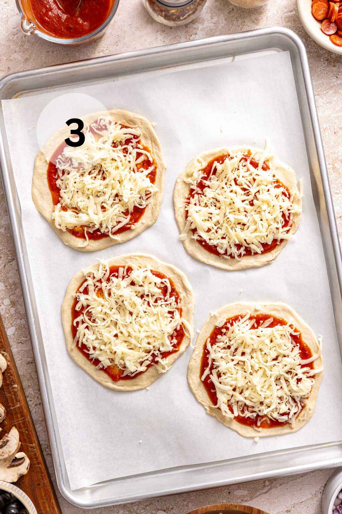 Adding shredded over size on small rounds of dough.