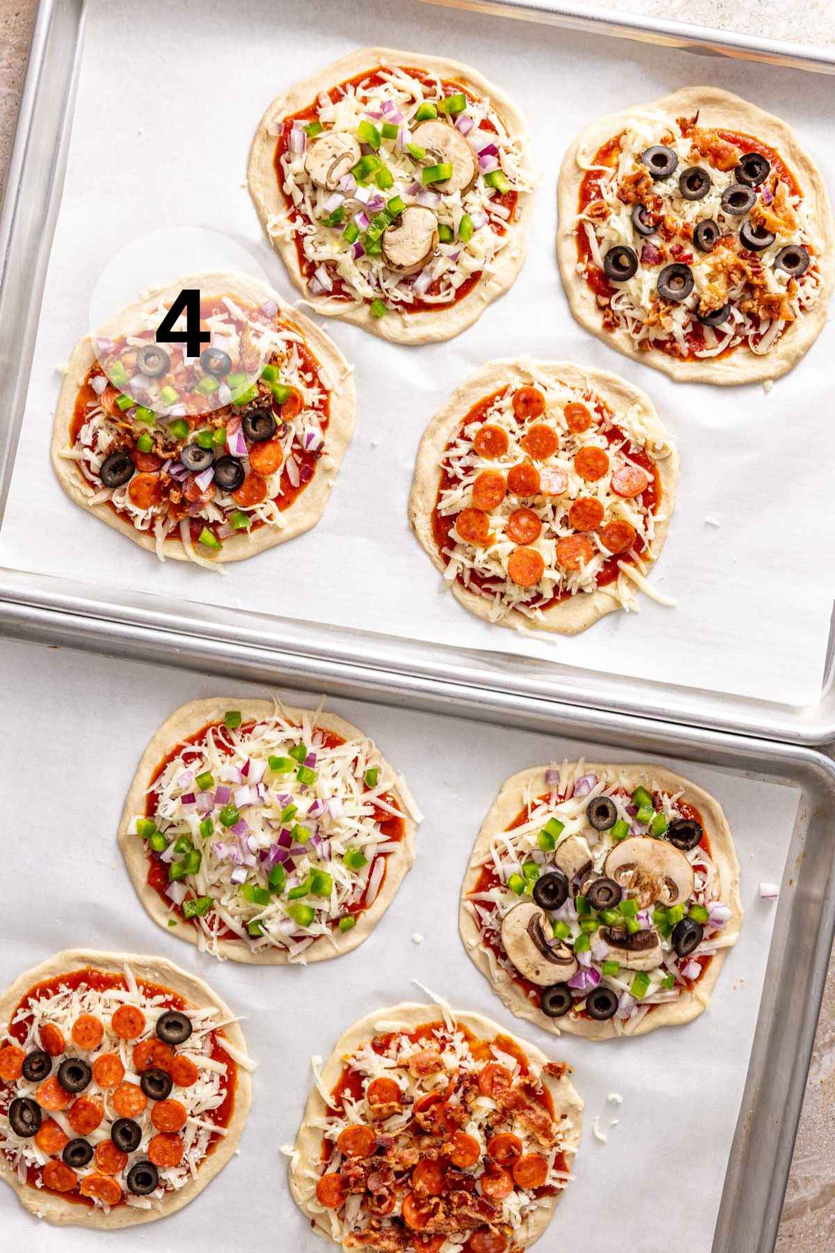 Mini pizzas on sheet pans before being cooked.