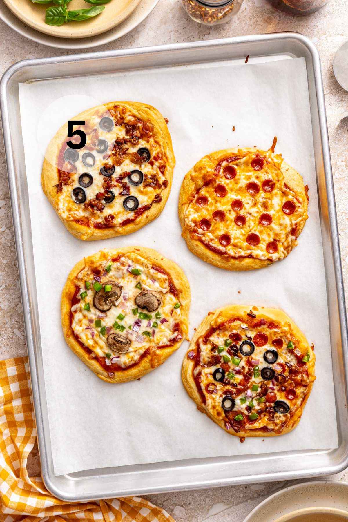 Mini pizzas on a parchment-lined sheet pan.