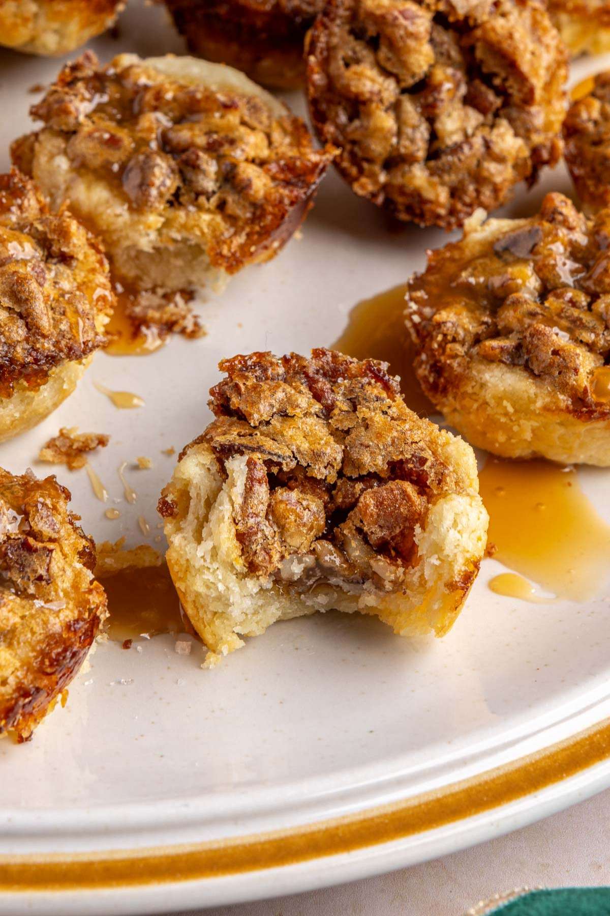 Pecan tarts on a plate with a bite taken out of one.