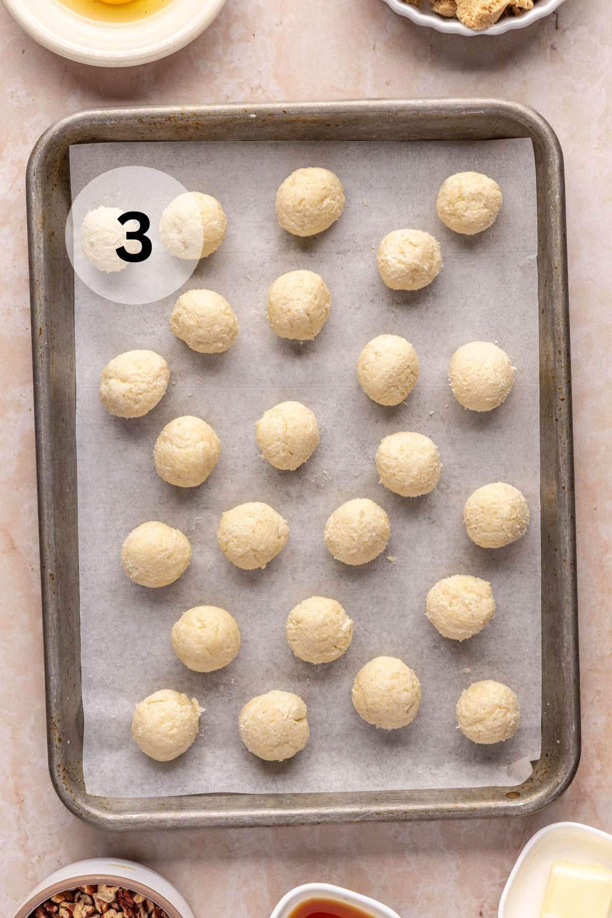 Balls of dough on a parchment-lined pan.
