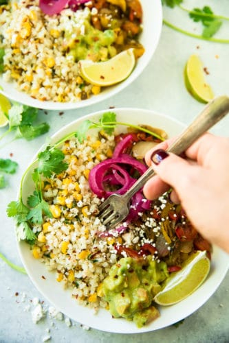 Delicious and simple to make Vegan Burrito Bowls — with a combination of fajita veggies, riced cauliflower and your favorite burrito toppings, an easy, flavorful meal will be yours in under 20 minutes! 
