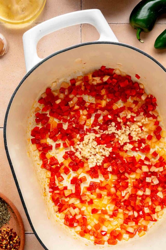 Adding minced garlic to sautéing pepper and onion.