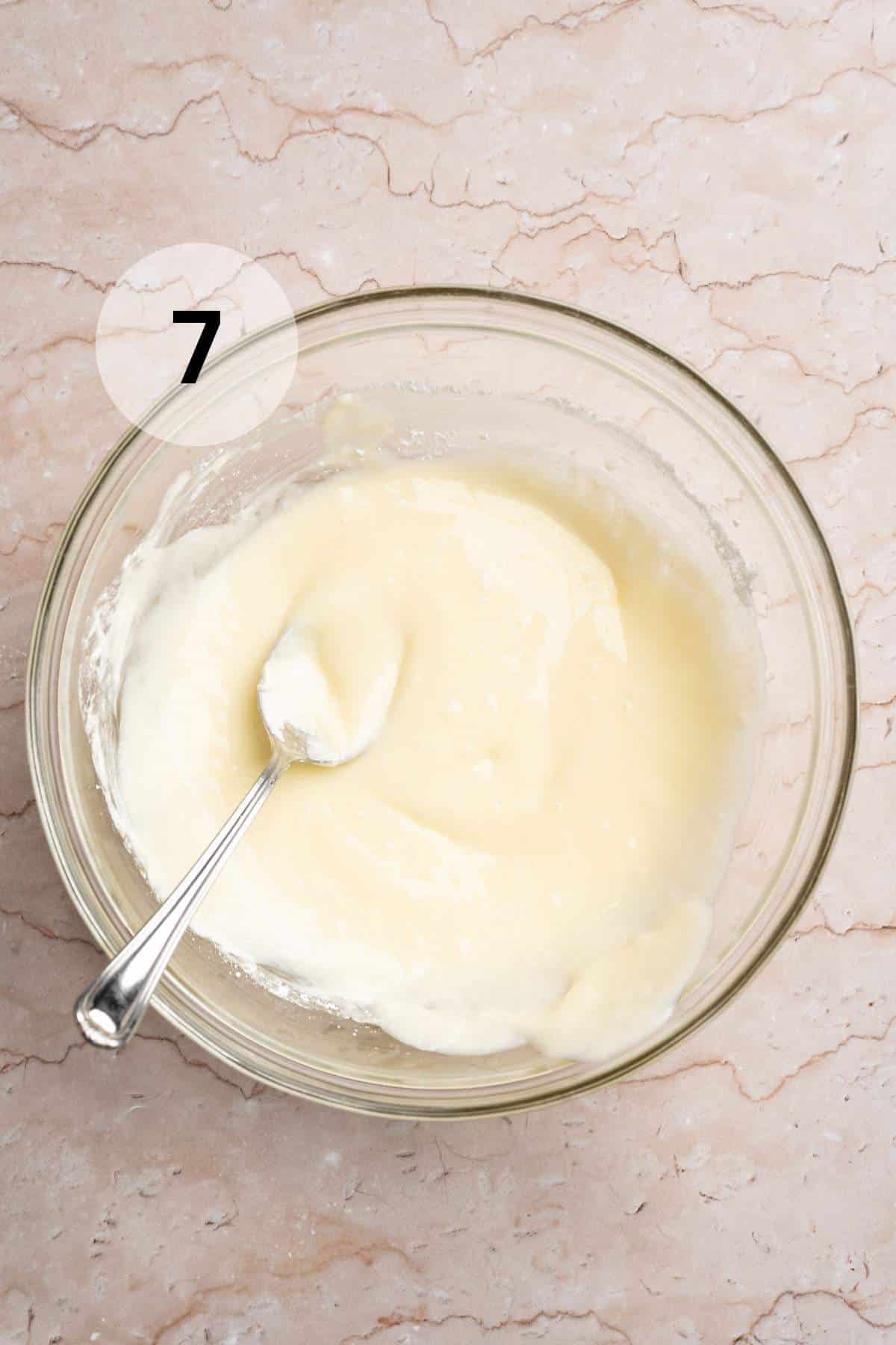 Stirring together cream cheese with powdered sugar in a large bowl.