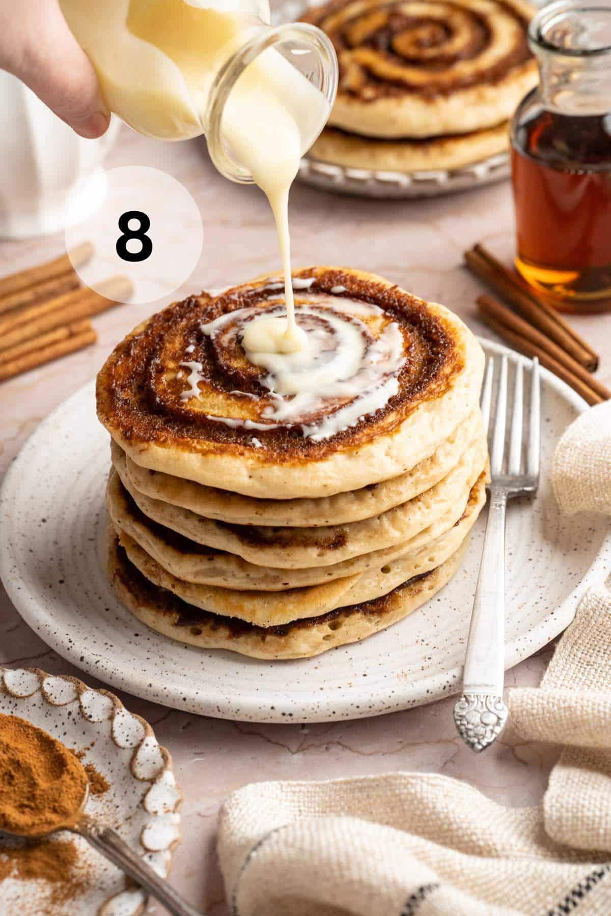 Drizzling cream cheese glaze over cinnamon swirl pancakes.