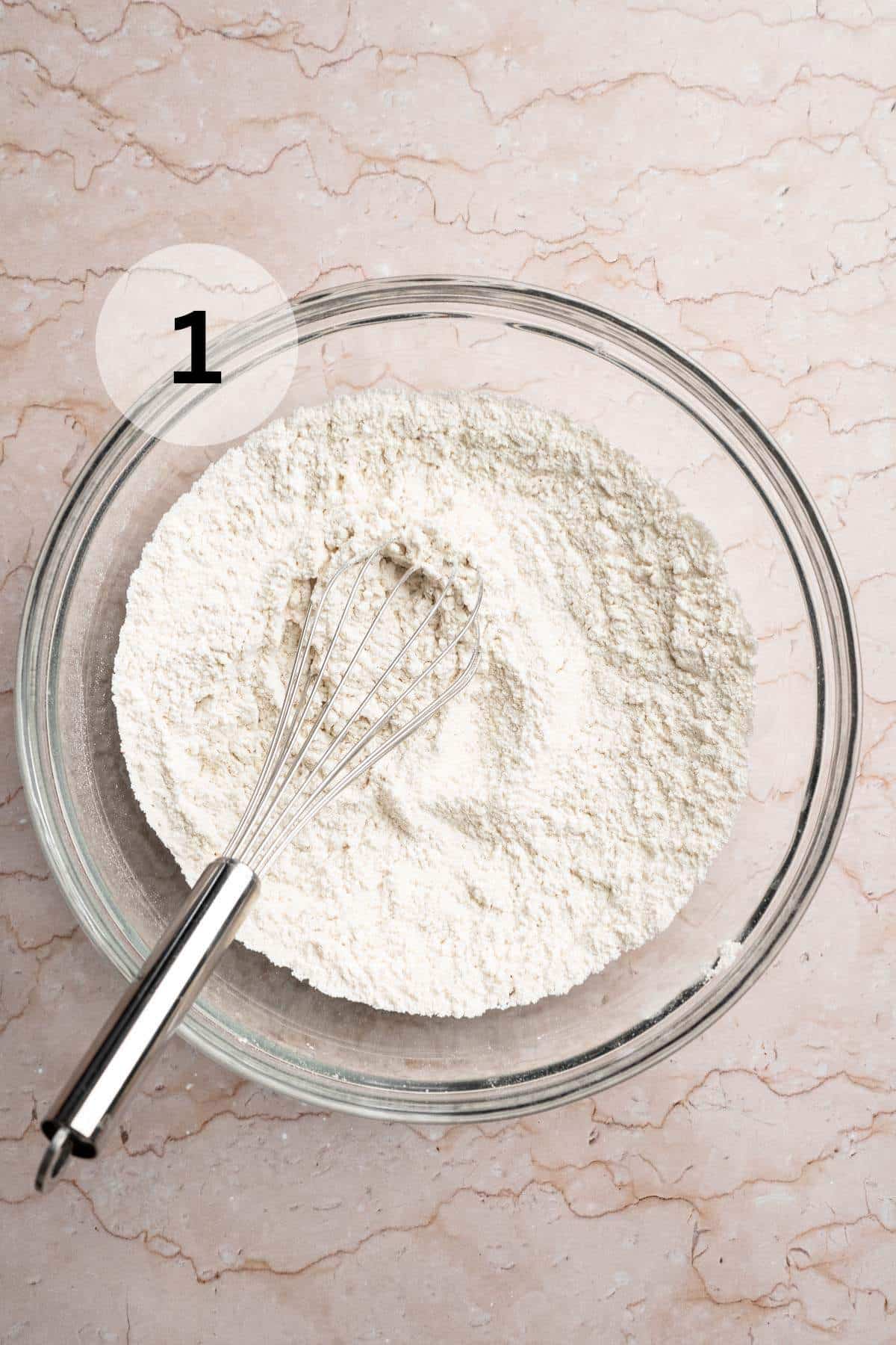 Using a whisk to mix flour with baking soda and baking powder in a large bowl.