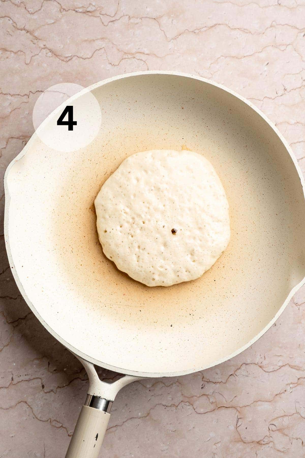 A pancake cooking in a skillet.