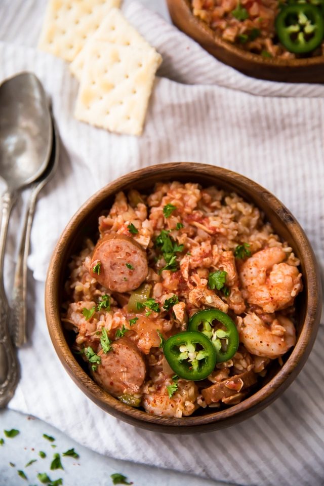Slow Cooker Jambalaya served in a wooden bowl with silver spoons on the side