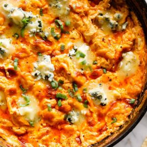 Buffalo Chicken Dip in a skillet topped with blue cheese crumbles.
