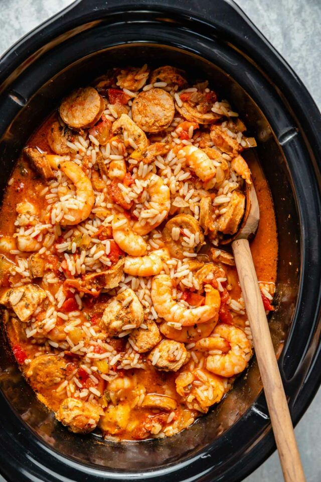 Stirring shrimp and rice in a slow cooker.