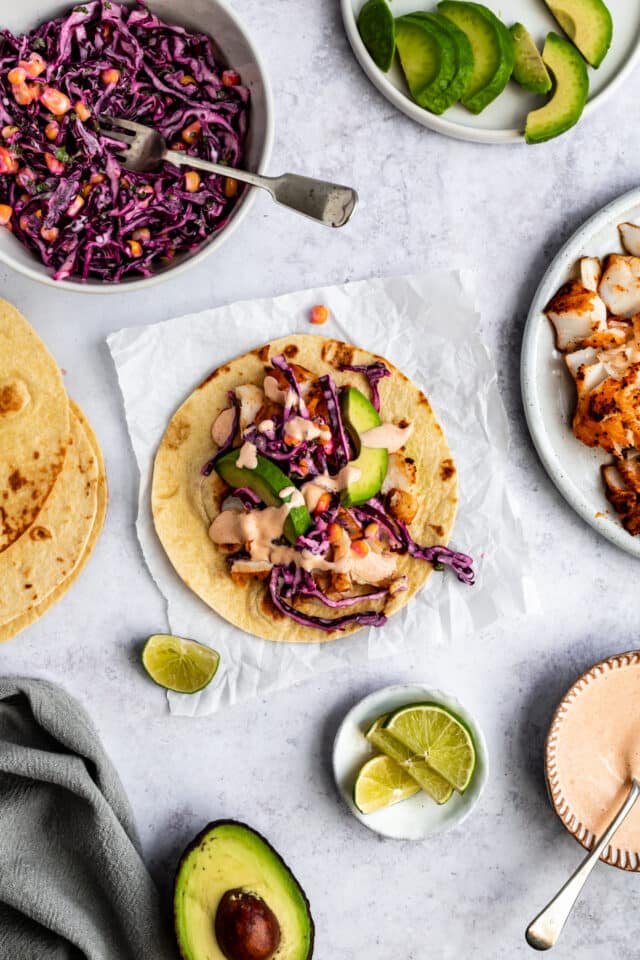 making fish tacos with corn tortillas and cod, slaw and creamy sauce