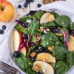 spinach salad topped with blueberry and apple slices
