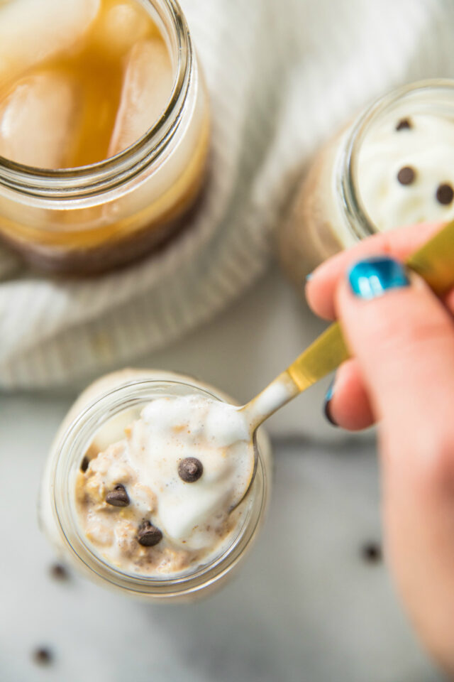closeup of woman's hand spooning out a bite of Cold Brew Coffee Overnight Protein Oats