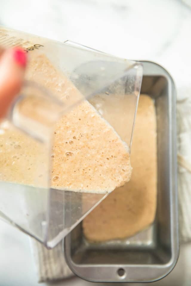 Low batter of Low Fat Flourless Banana Bread being poured from a blender into a loaf pan