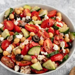 chickpea salad with tomatoes and cucumber in a large white serving bowl