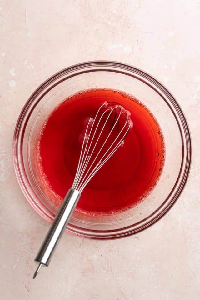 Whisking Jell-O mix with boiling water in a large bowl.