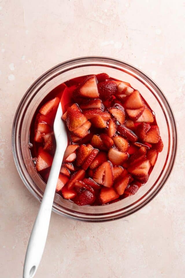 Stirring fresh strawberries into jello mixture.
