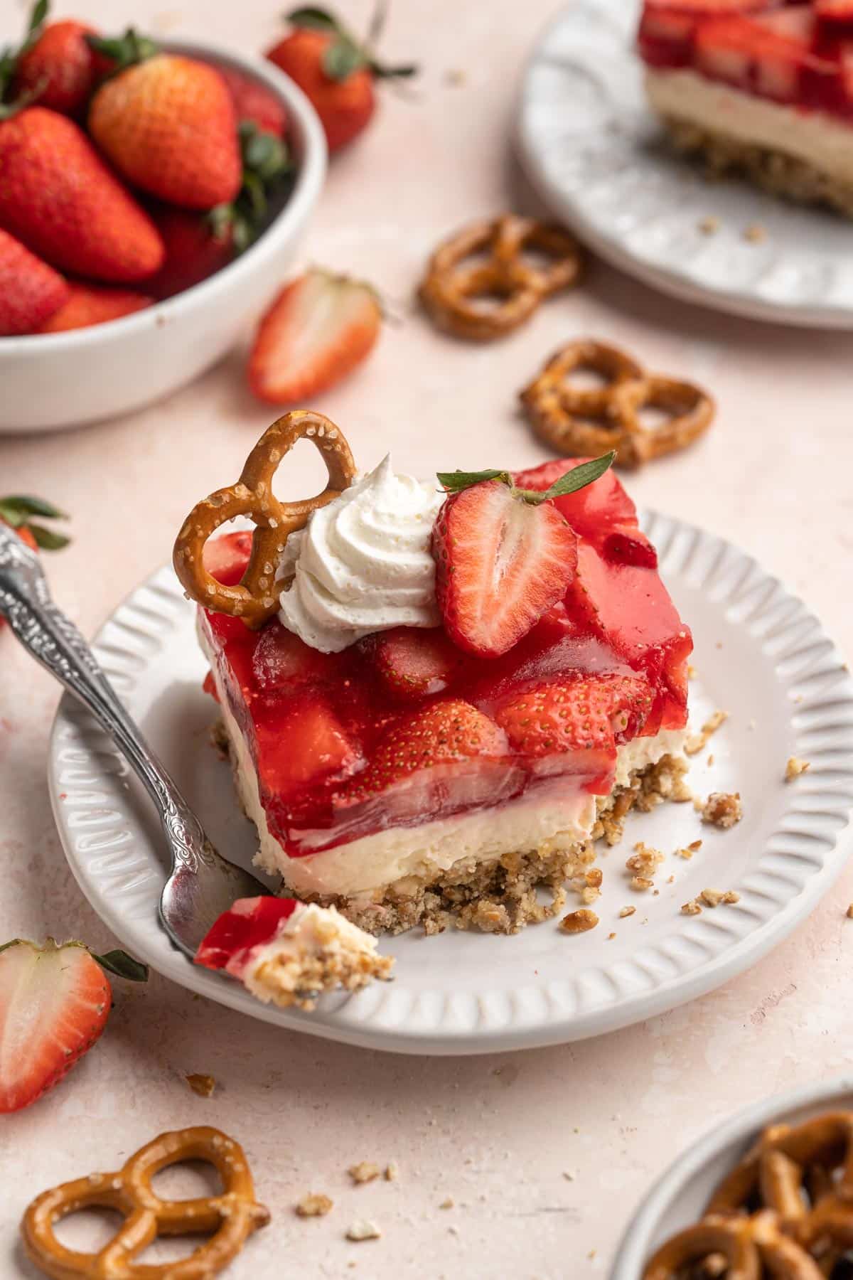 Slice of strawberry pretzel salad on a white plate with a fork.