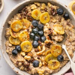 Bowl of oatmeal topped with banana slices, blueberries and mini chocolate chips.