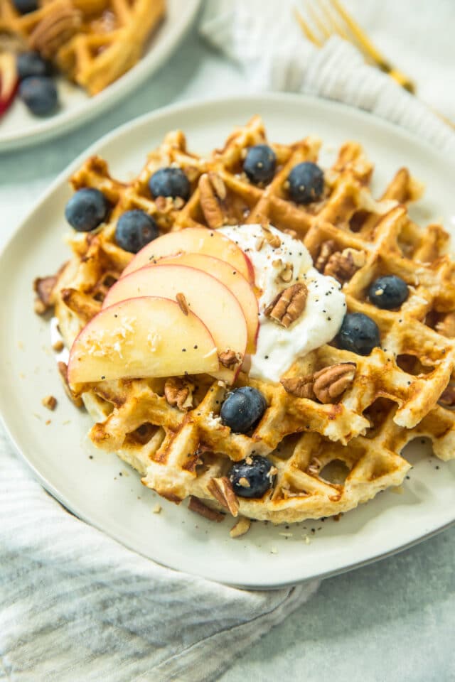 Healthy Protein Waffle Recipe topped with Greek yogurt, sliced apple, pecans and blueberries
