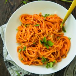 Vegan Roasted Red Pepper Pasta Sauce over pasta in a white bowl with gold fork