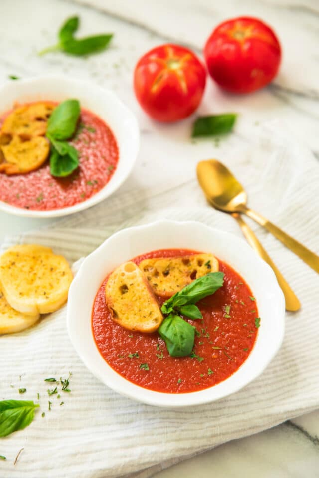 Healthy Roasted Tomato Basil Soup in white bowls with gold spoons