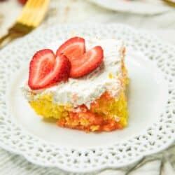 a piece of Easy Strawberry Lemonade Poke Cake on a white plate with two strawberry slices on top