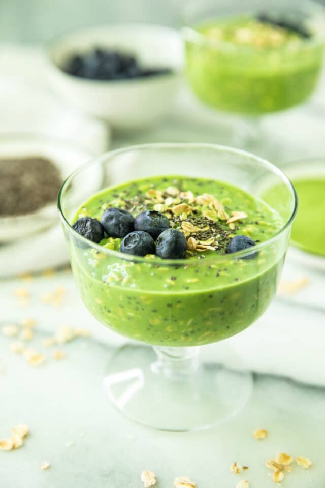 Matcha Collagen Overnight Oats in a glass, topped with oats, blueberries and chia seeds