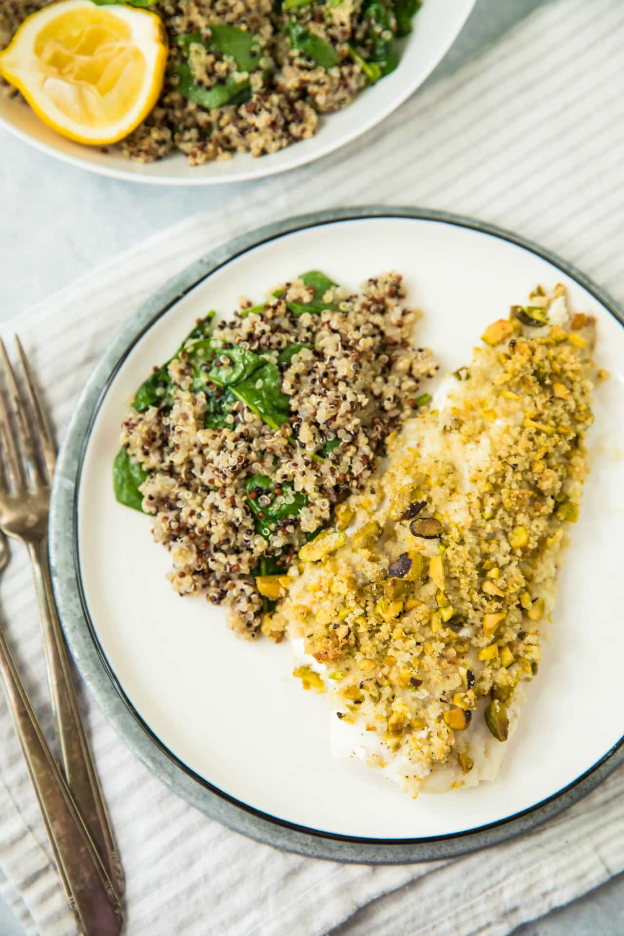 Healthy Pistachio Crusted White Fish served with quinoa on a white plate