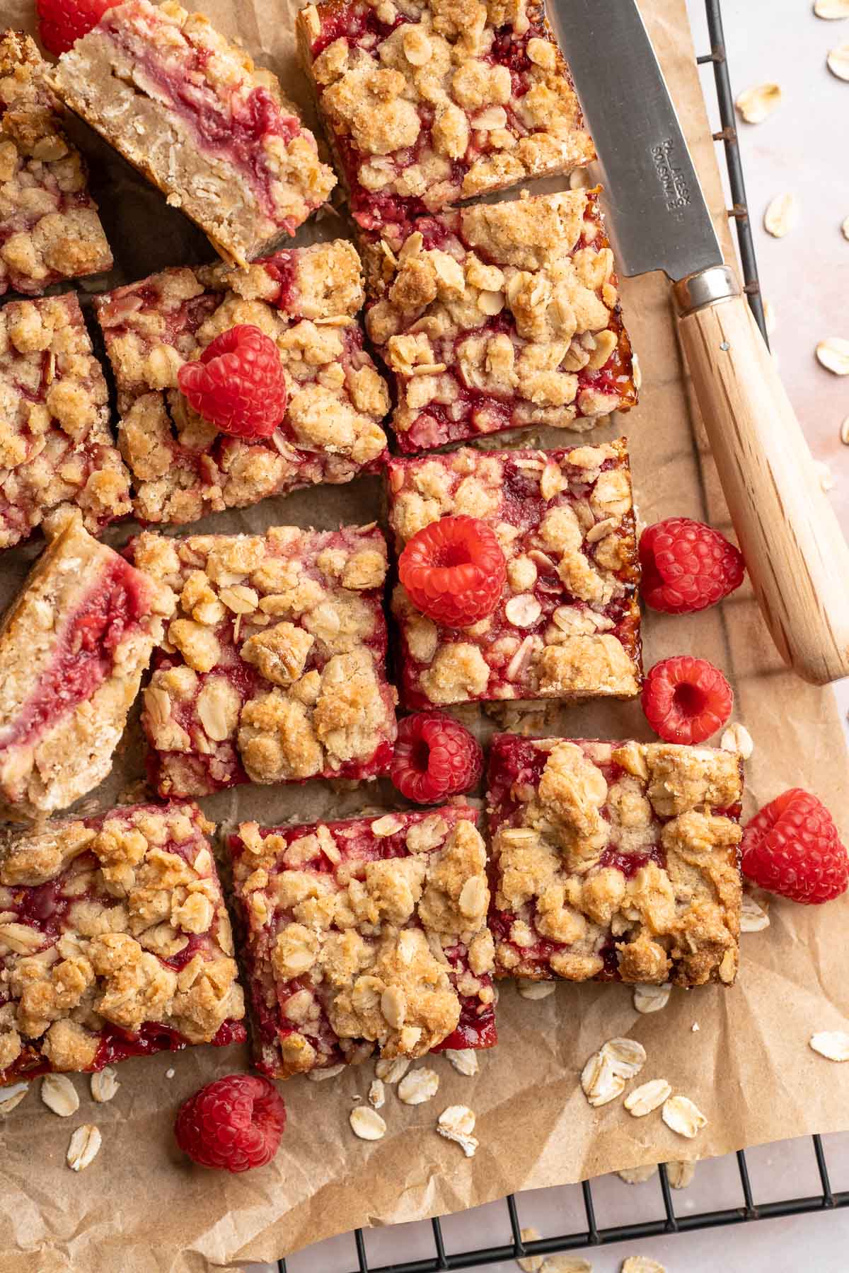 Sliced raspberry crumble bars on parchment paper.