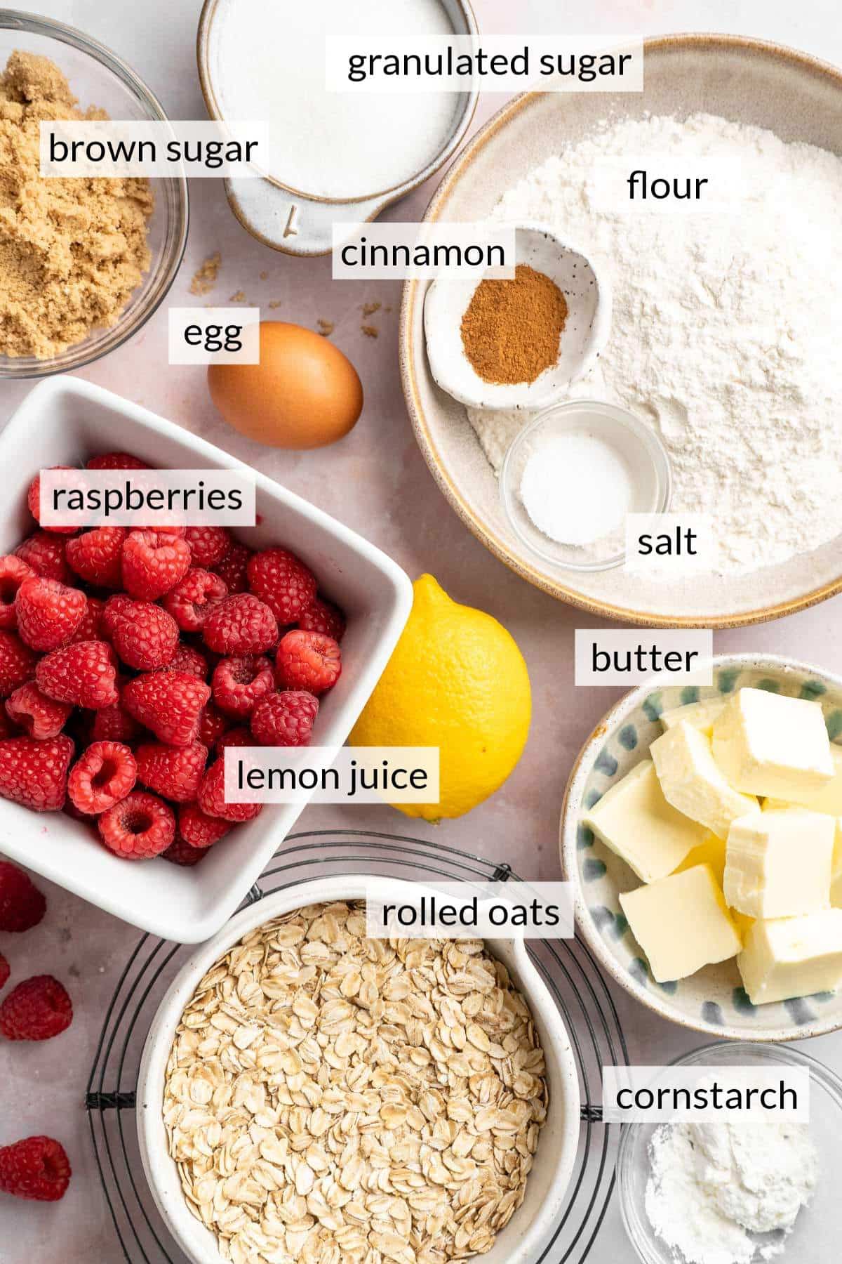 Bowls of flour, fresh raspberries, butter, sugar and oats.
