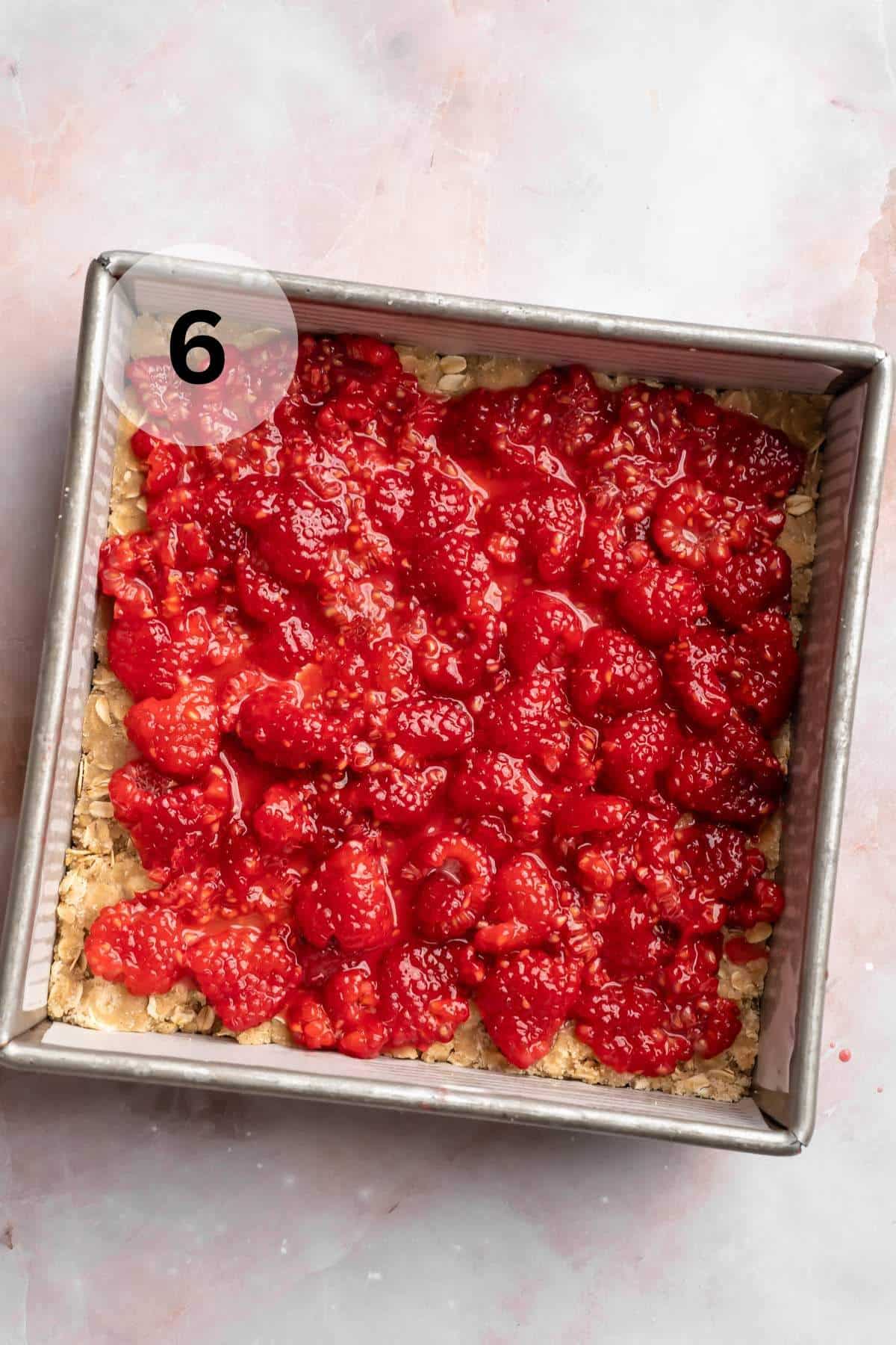 Raspberry filling spread over crust in a square pan.