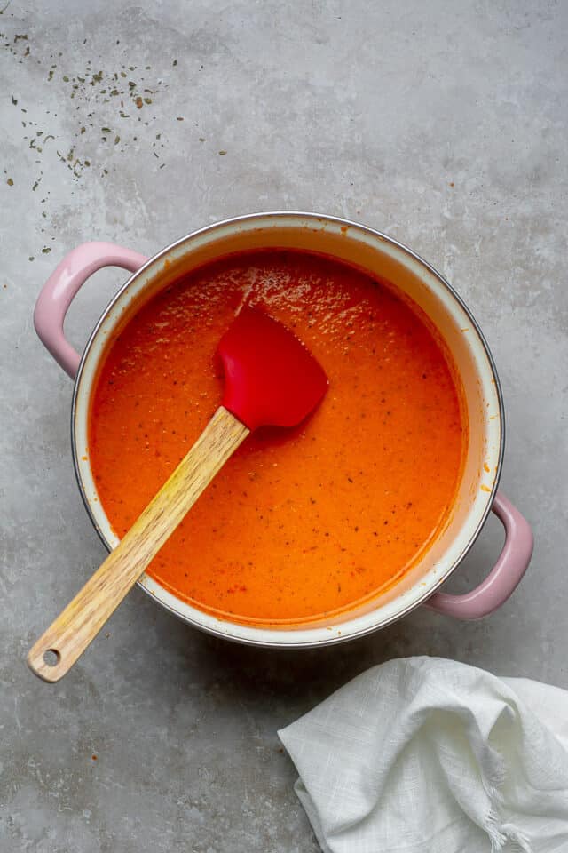 Stirring creamy roasted red pepper sauce.