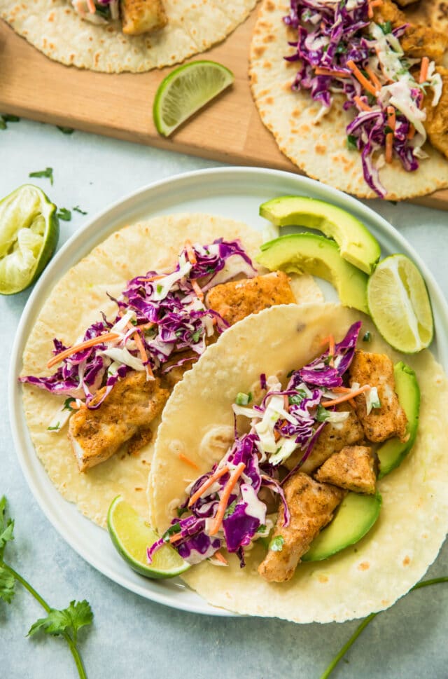 Healthy Blackened Baja Fish Tacos on a white plate served with avocado slices