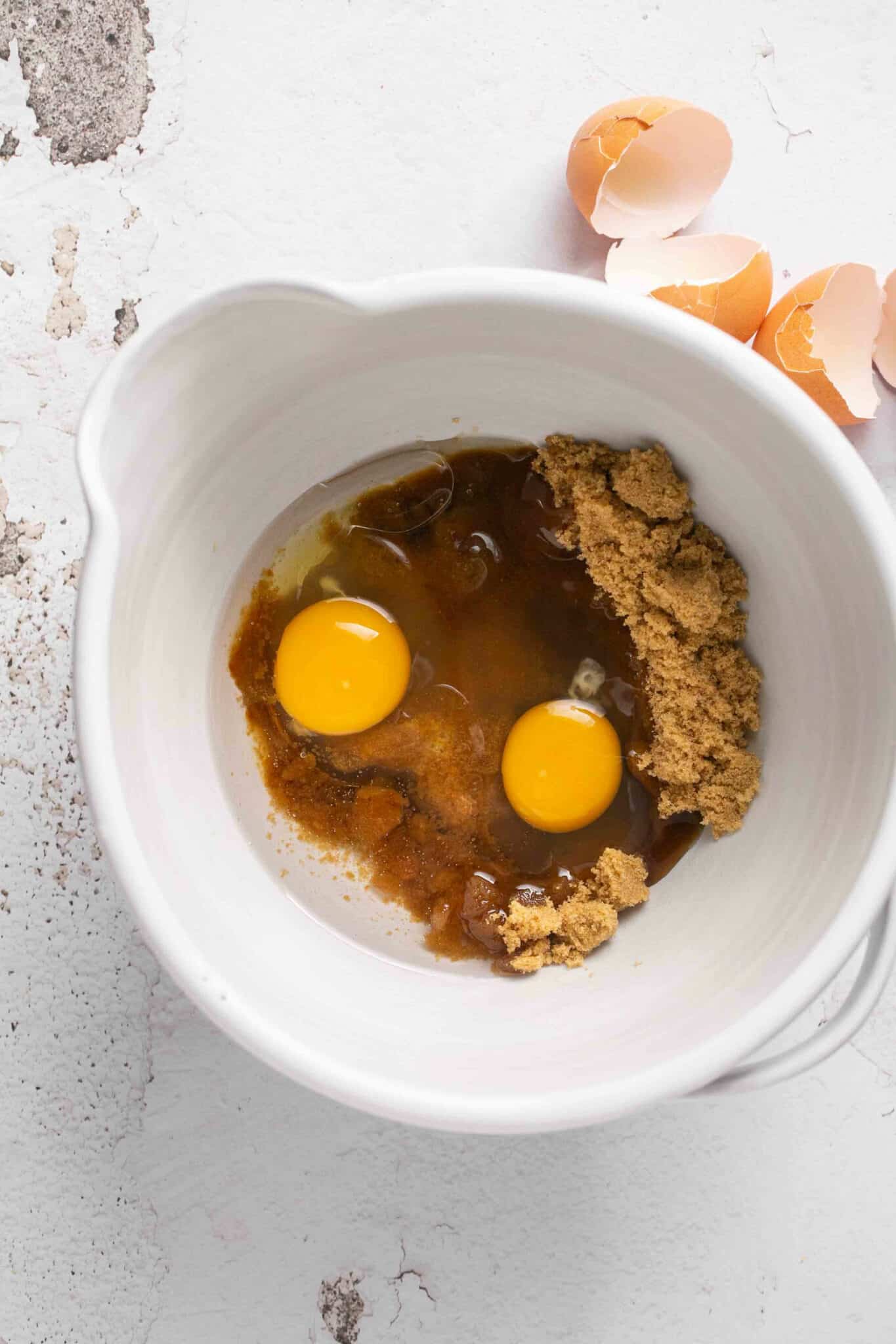 Eggs in a bowl with oil and brown sugar.