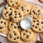 Gluten free chocolate chip cookies on a cooling rack with flaky sea salt.