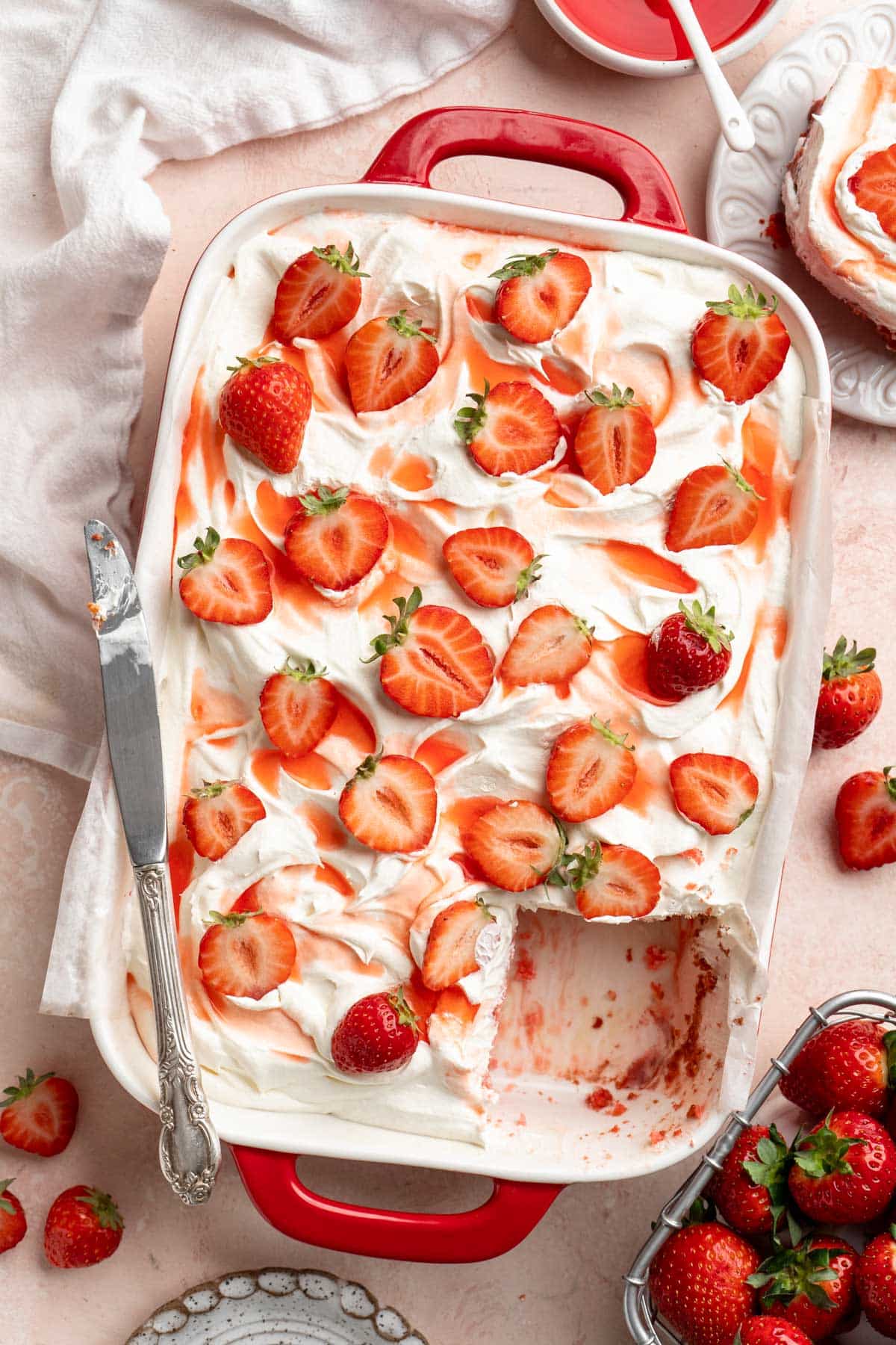 Strawberry poke cake with a slice removed.