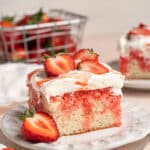 Slice of strawberry poke cake on a white plate.