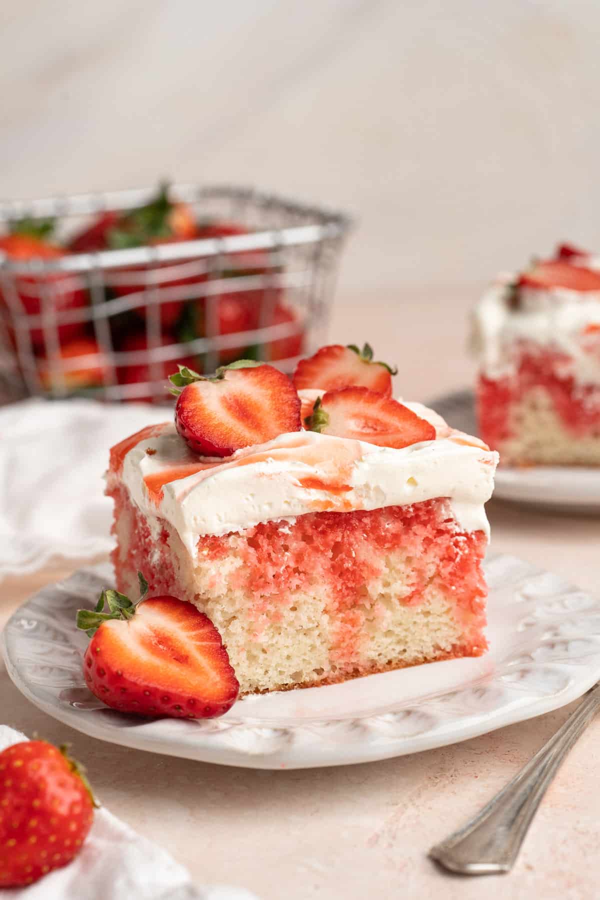 Slice of strawberry poke cake on a white plate.