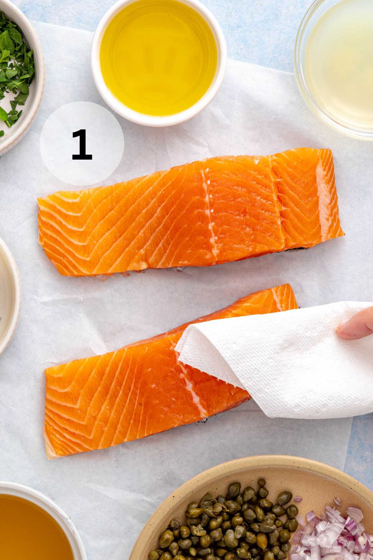Patting salmon fillets dry with a paper towel.
