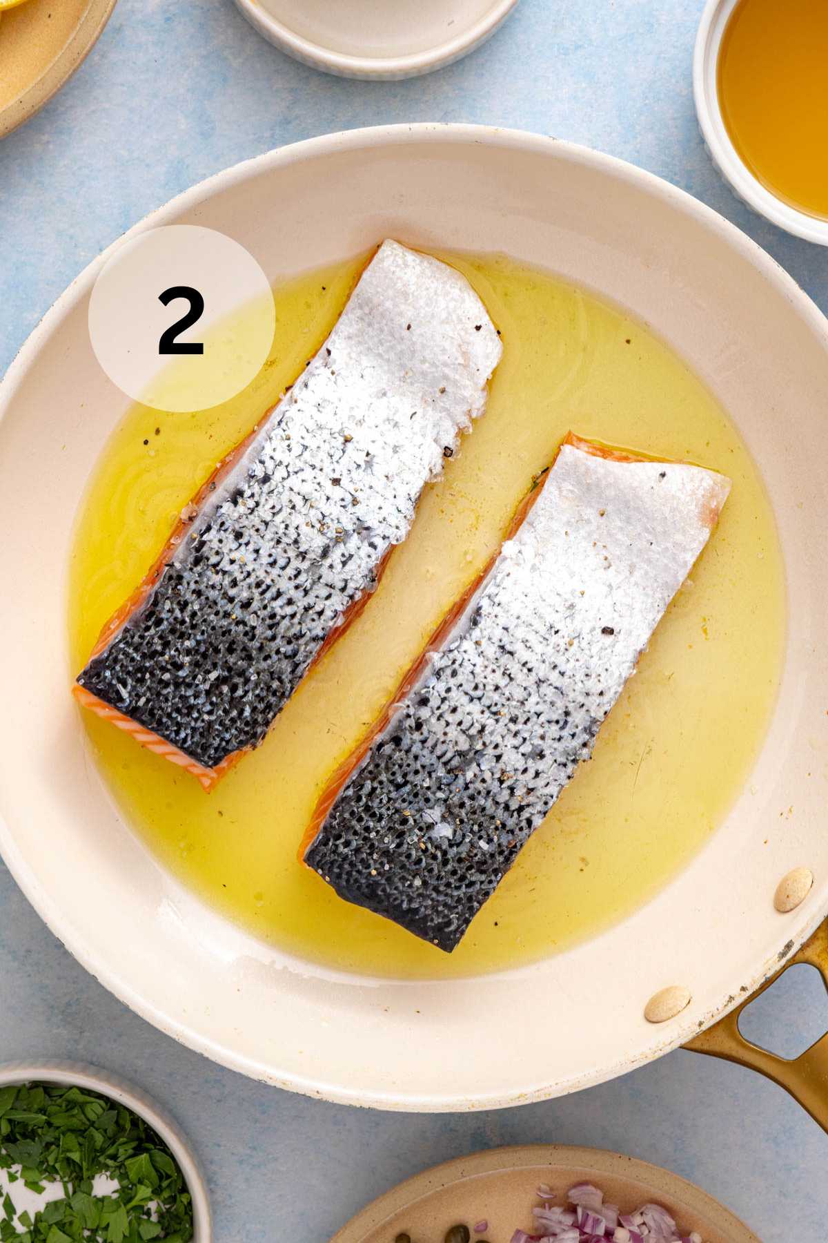 Salmon cooking flesh side down in oil.