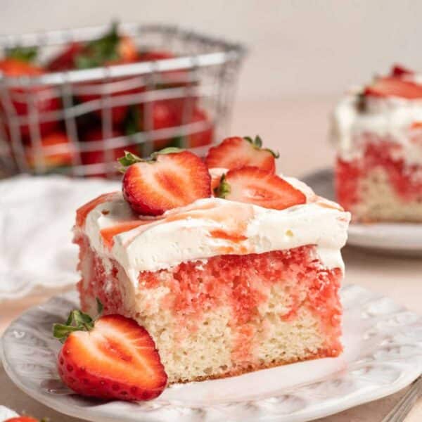 Slice of strawberry poke cake on a white plate.