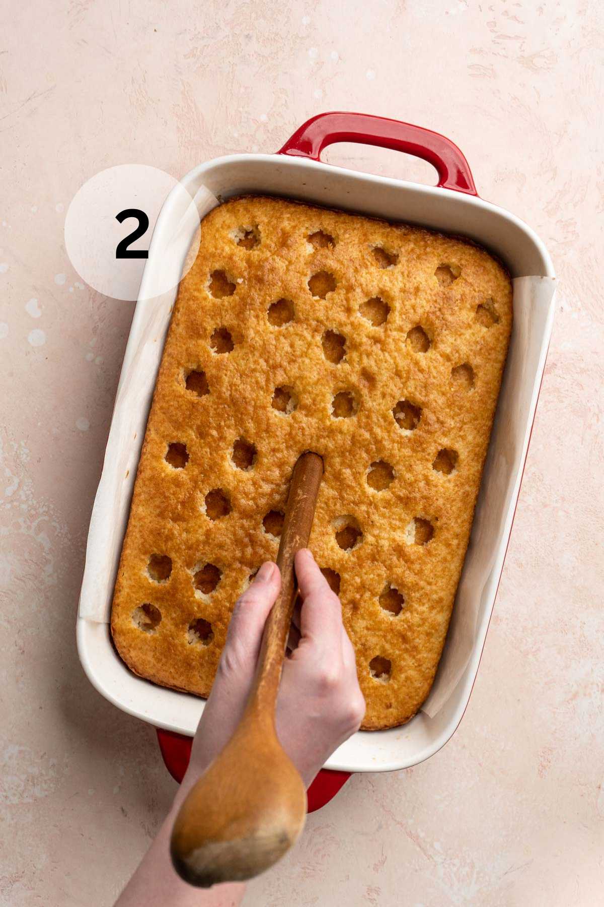 Poking holes in the top of a yellow cake.