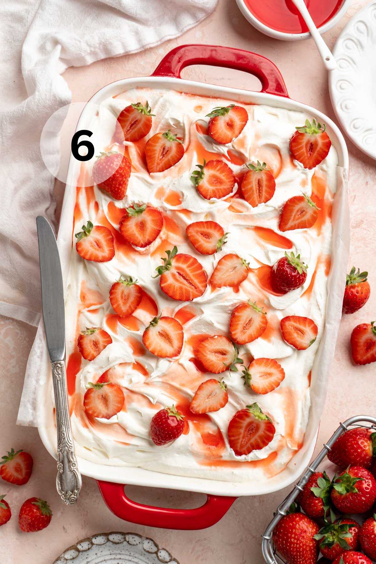 Strawberry poke cake topped with fresh strawberries and strawberry juice.