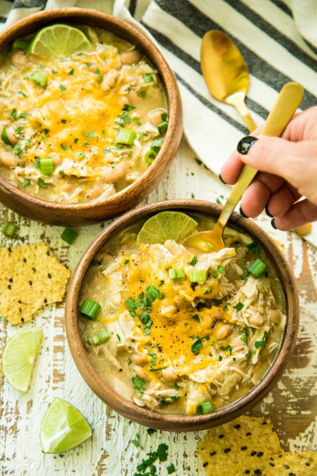 overhead view of woman's hand getting a spoonful of Gut-Healing Easy Slow Cooker White Chicken Chili