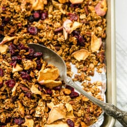 granola on a baking pan with a large silver spoon