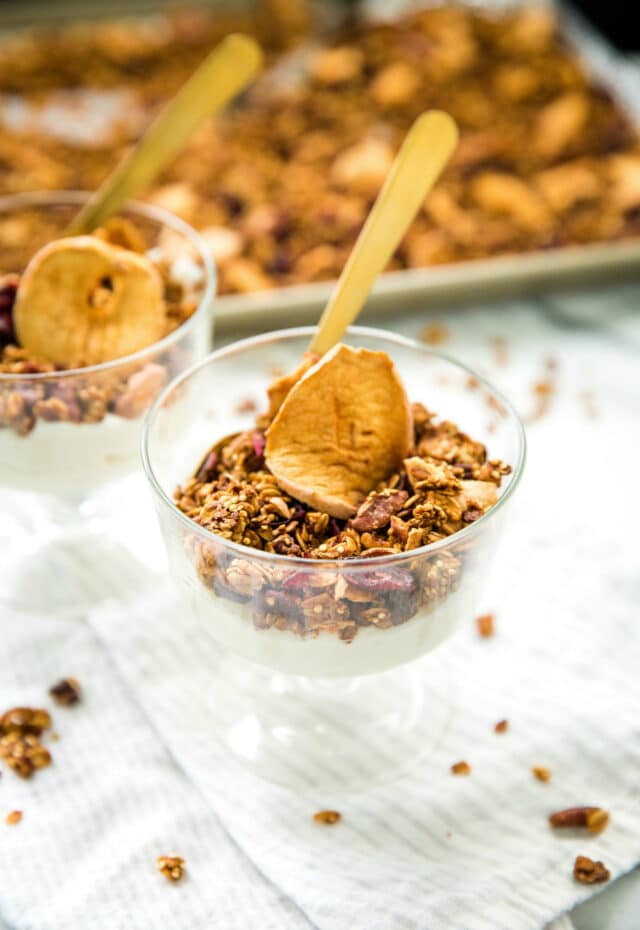side view of Apple Pecan Quinoa Granola and yogurt in a glass with a gold spoon
